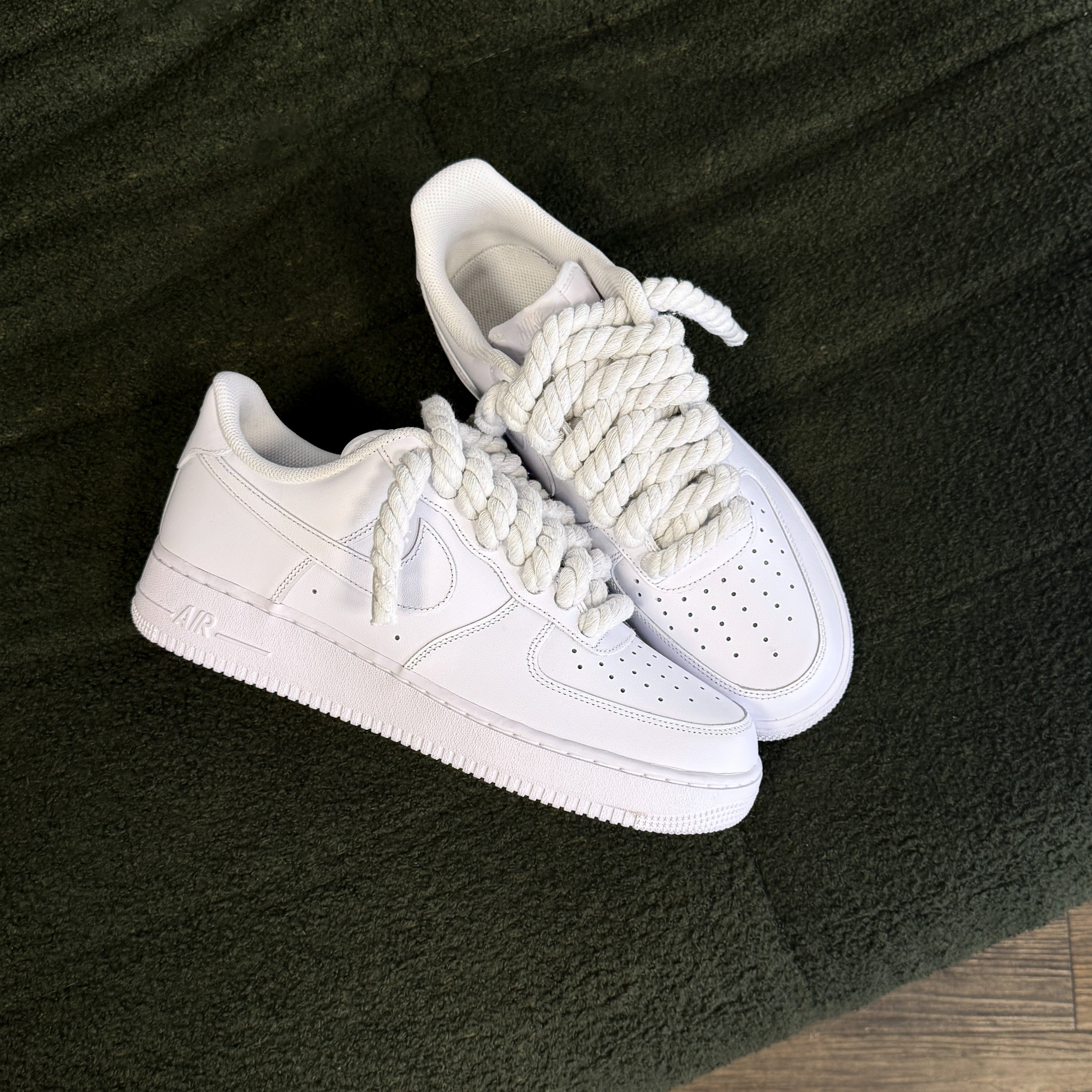 White sneakers with white laces on a dark green surface