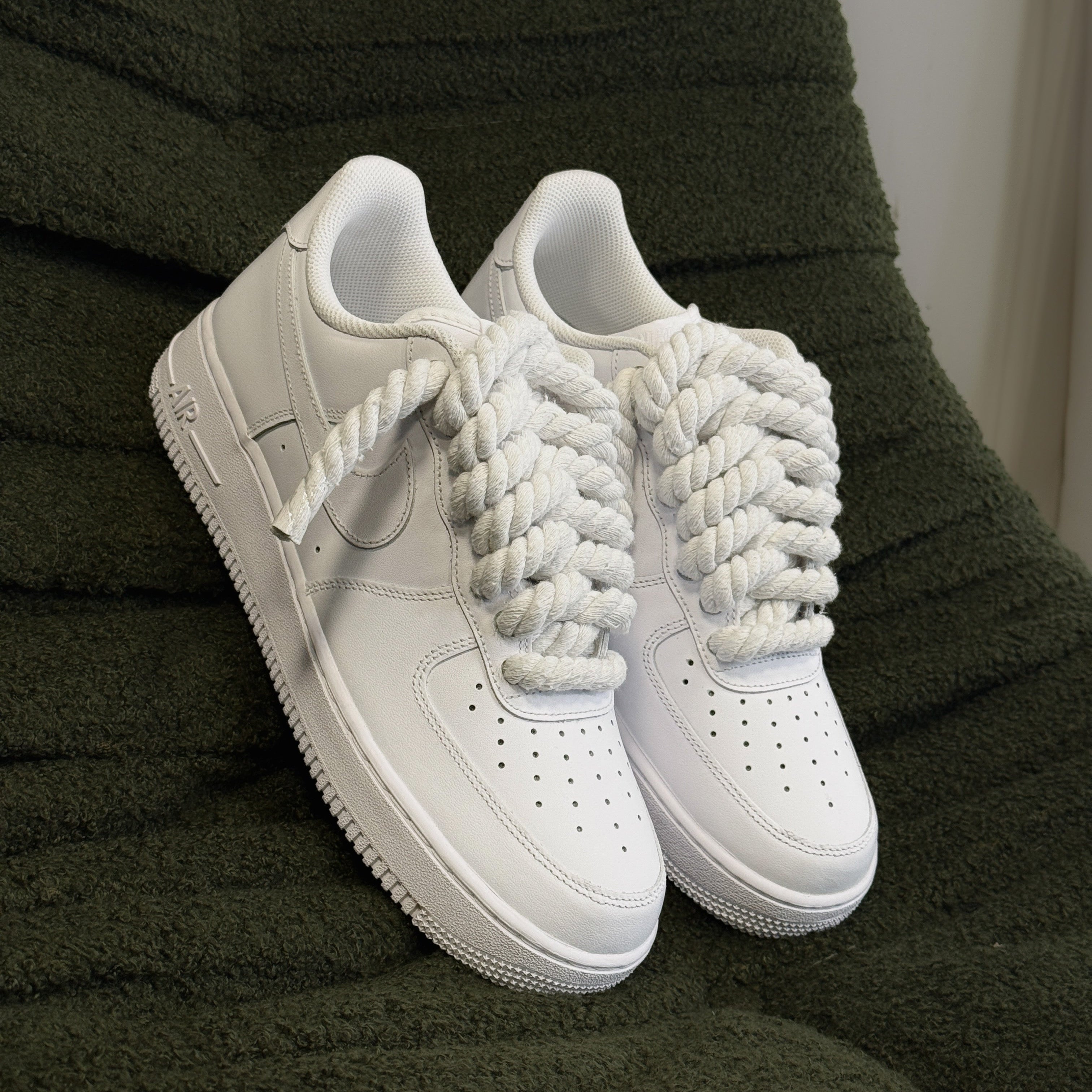 White sneakers with unique laces on a green textured surface