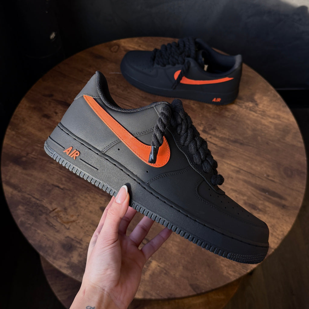 Black and orange sneaker on a wooden stool with a hand touching it