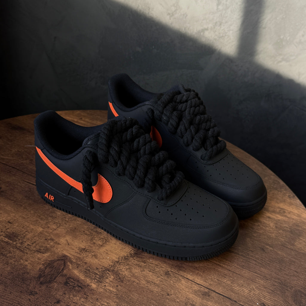 Black sneakers with orange accents on a wooden surface